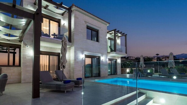 A modern two-story house with a swimming pool, outdoor seating, and a glass railing.