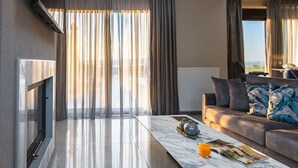 A modern living room with a marble coffee table, a sofa with patterned cushions, and a large window with sheer curtains.