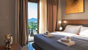 A hotel room with a large bed, a nightstand with a lamp, and a view of the outdoors.