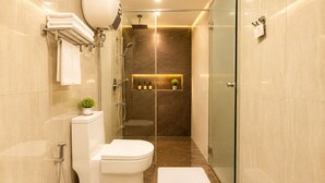 A modern bathroom with a toilet, shower, and glass-enclosed shower stall.