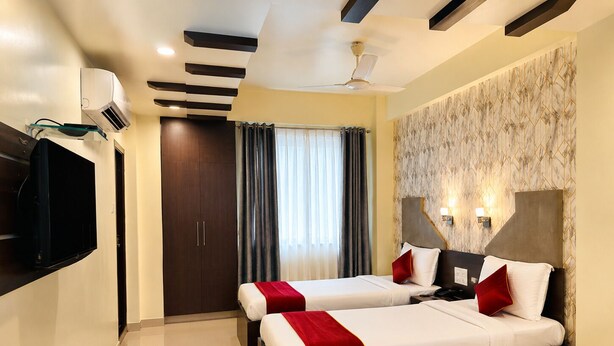 A hotel room with two beds, a flat-screen TV, a ceiling fan, and a large window with curtains.