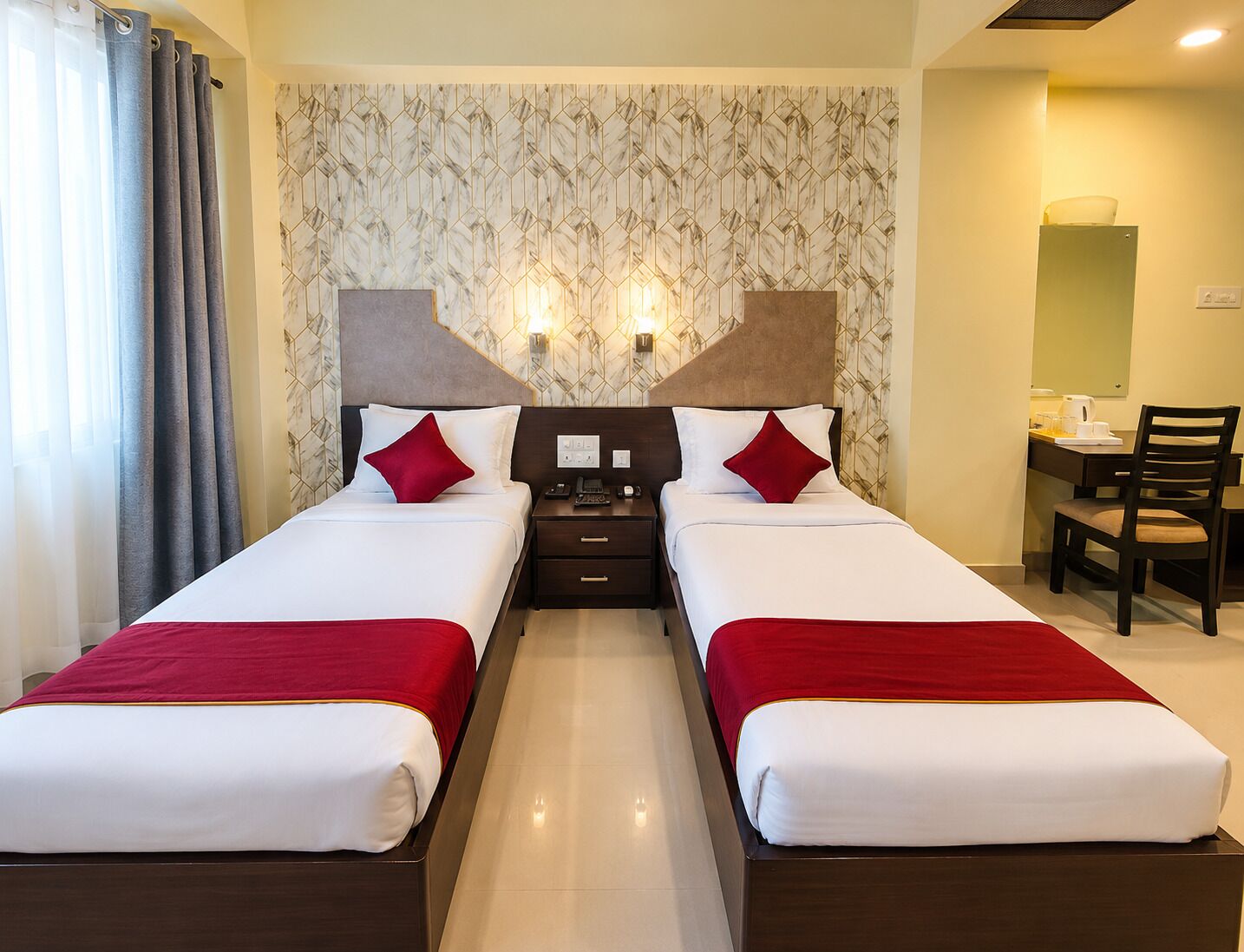 Une chambre d’hôtel avec deux lits, un bureau et une chaise.