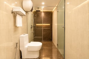 A modern bathroom with a toilet, a glass shower enclosure, and a marble-tiled floor. - Hotel Chariot Inn Patna (Patna)