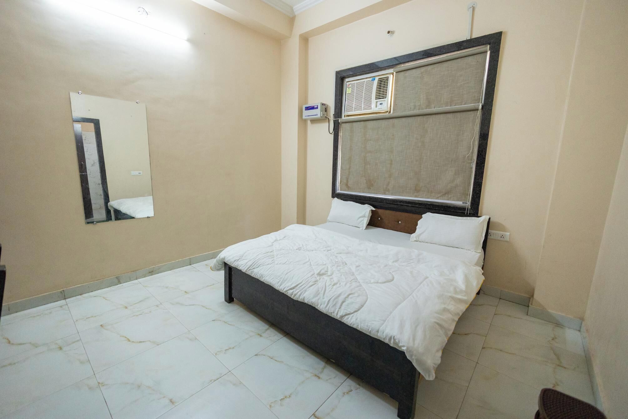 A bedroom with a bed, a mirror, and an air conditioning unit.