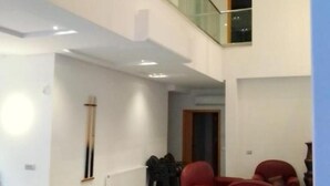 A spacious room with a long dark table, red chairs, and a glass railing overlooking a lower level.