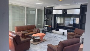 A modern living room with leather sofas, a flat-screen TV, and a marble floor.