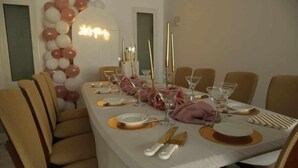 A dining table set with white tablecloth, gold cutlery, and pink napkins.