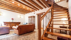 A spacious living area with a wooden staircase, a fireplace, and a large window. - Al Campanile View and Terrace by Wonderful Italy (Venice)