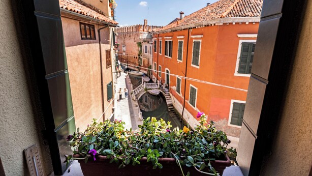 A narrow Venetian canal with buildings on either side, a small bridge, and a balcony with potted plants. - Al Campanile View and Terrace by Wonderful Italy (Venice)