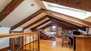 A loft bedroom with exposed wooden beams, a wooden desk, a bed, and a skylight. - Al Campanile View and Terrace by Wonderful Italy (Venice)