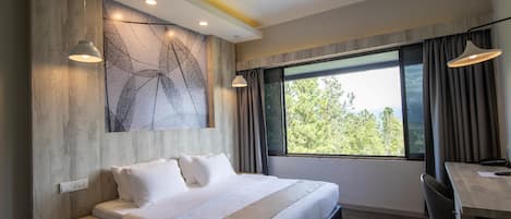 A hotel room with a bed, a desk, a chair, a ceiling fan, and a large window with curtains.