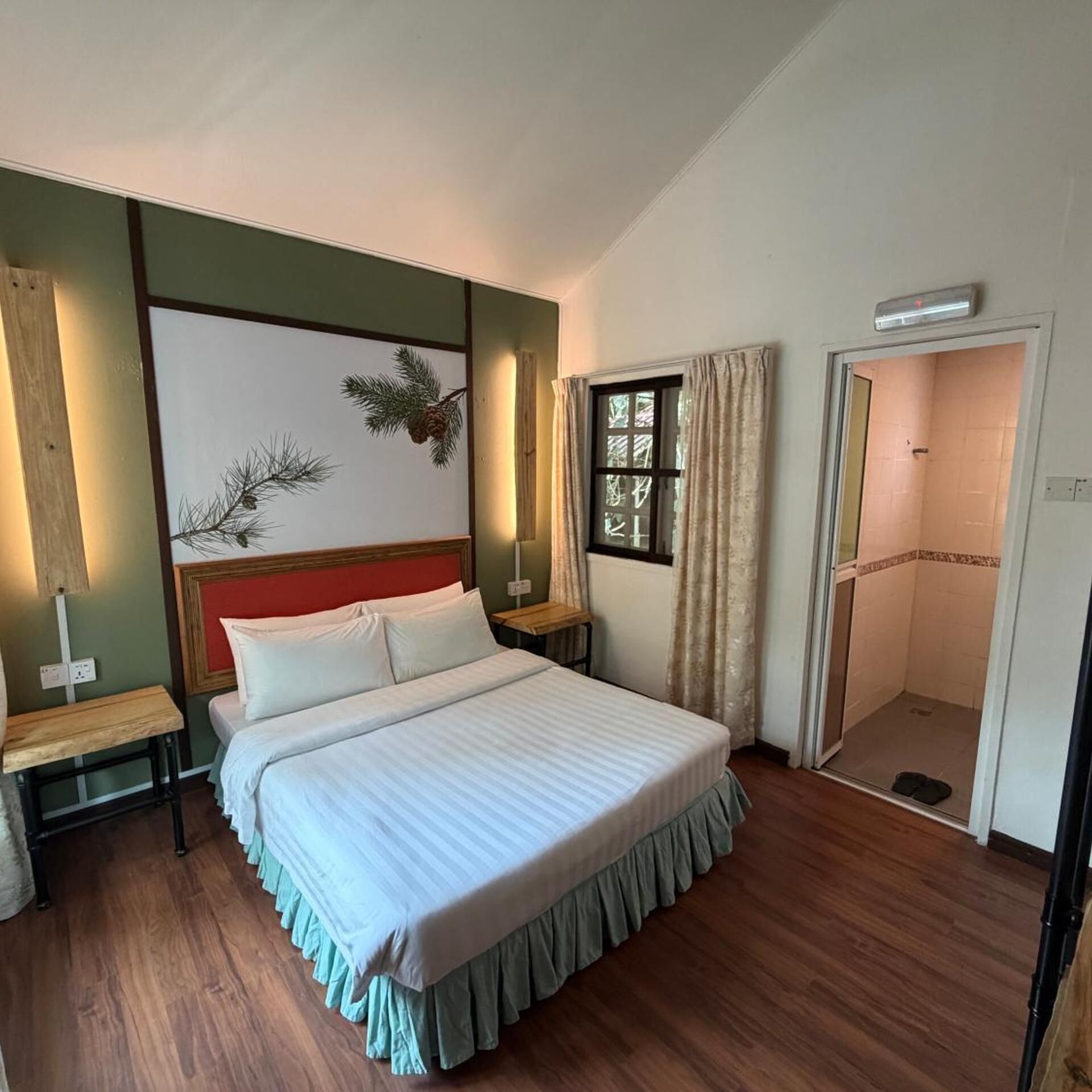 Une chambre à coucher comprenant un lit, des tables de chevet, une fenêtre avec des rideaux, une porte et un luminaire fixé au mur.
