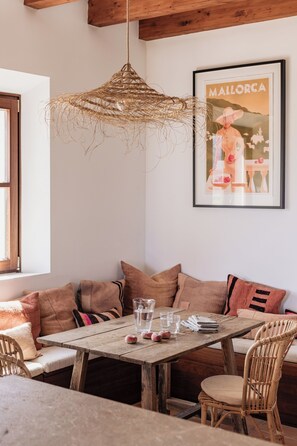 Cozy dining area with a rustic table set for two, featuring wicker chairs and cushioned benches.