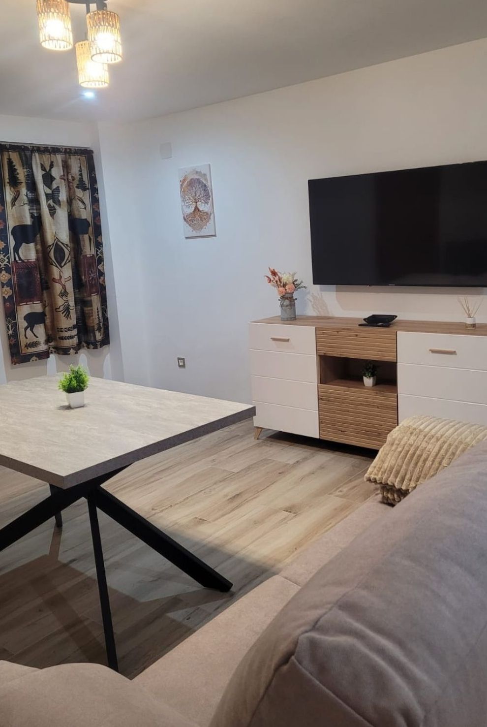 Una sala de estar moderna con un sofá, una mesa de comedor y un televisor montado en la pared.