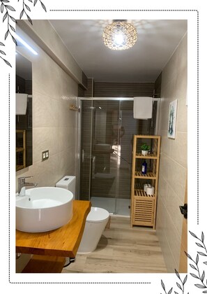 Features a sleek sink, separate toilet, and glass shower enclosure.