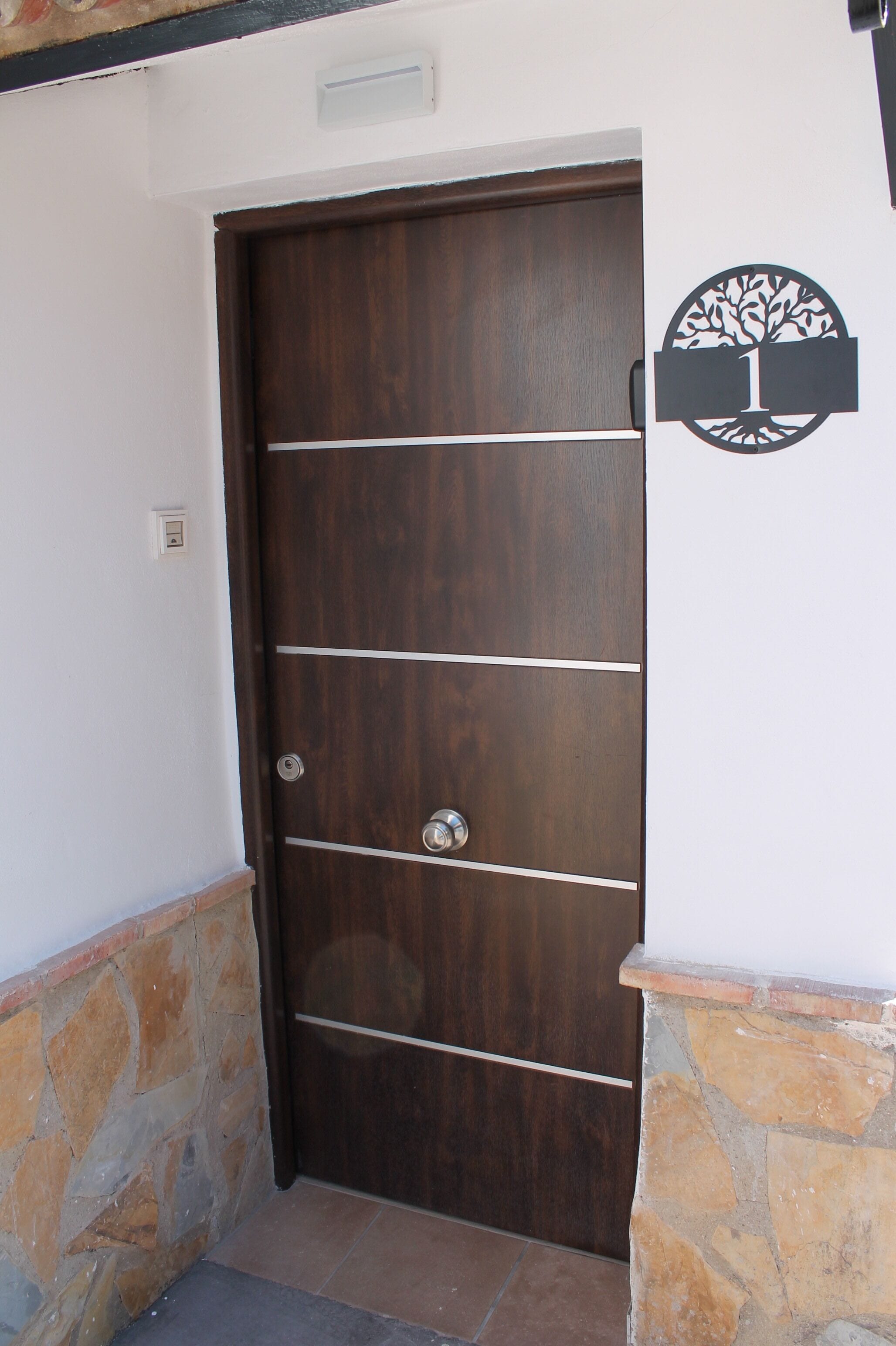 Eine Holztür mit horizontalen Metallstreben und einem runden Logo an der rechten Wand.