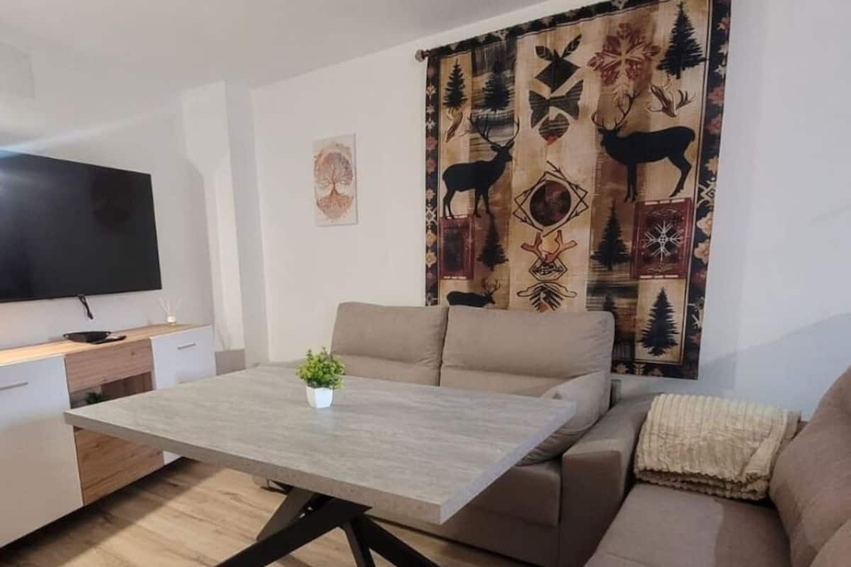 Ein modernes Wohnzimmer mit einer Couch, einem Couchtisch und einem Fernseher.