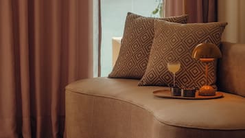 Een gezellige kamer met een zachte zithoek, een lamp en uitzicht op een waterpartij door grote ramen.