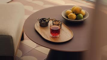 Une table ronde sur laquelle se trouve un plateau avec un verre contenant un liquide rouge, un bol de citrons et un petit pot de noix.