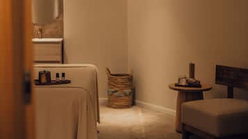 A small, cozy room with a bed, a chair, a small table, and a basket.
