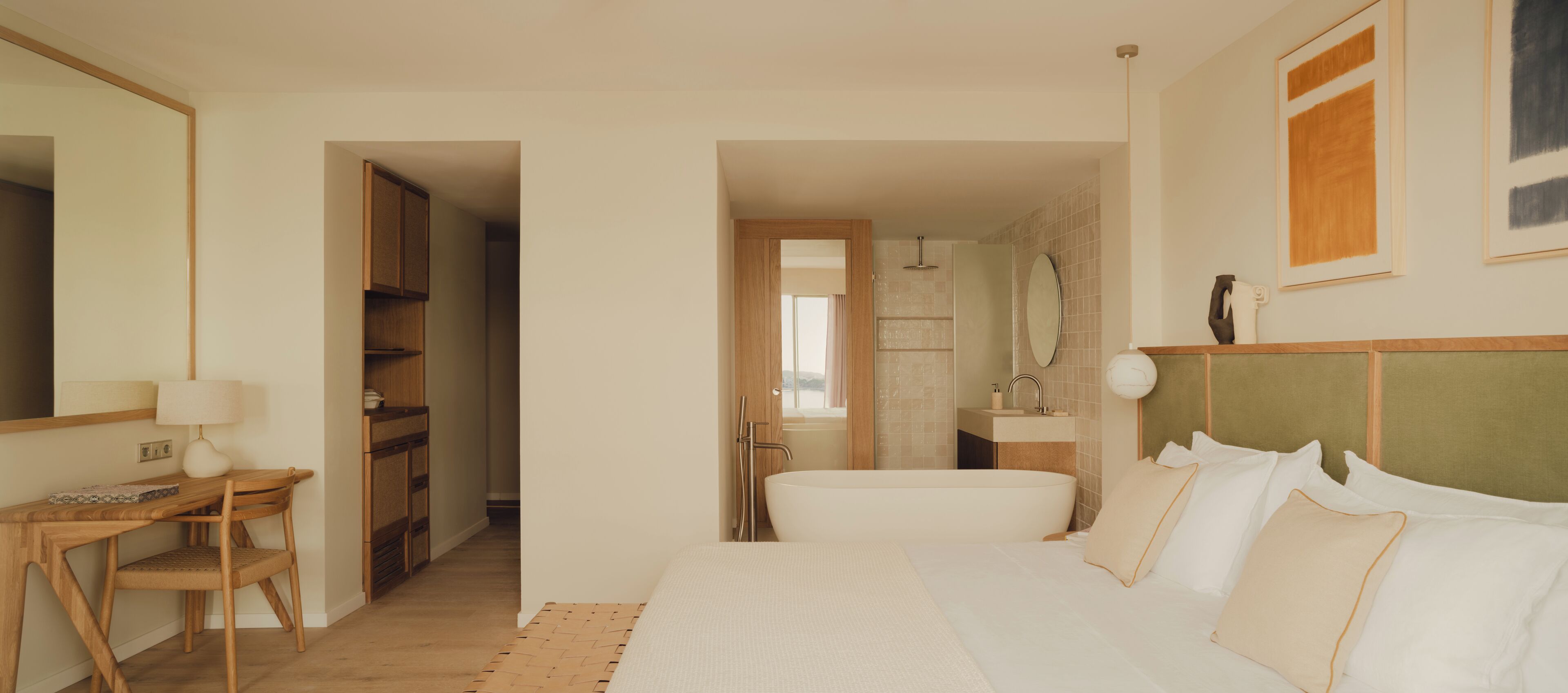 A bedroom with a bed, bedside table, lamp, and a view of the bathroom.