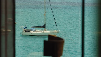 A view of a sailboat on calm waters, with a mountainous landscape in the background.
