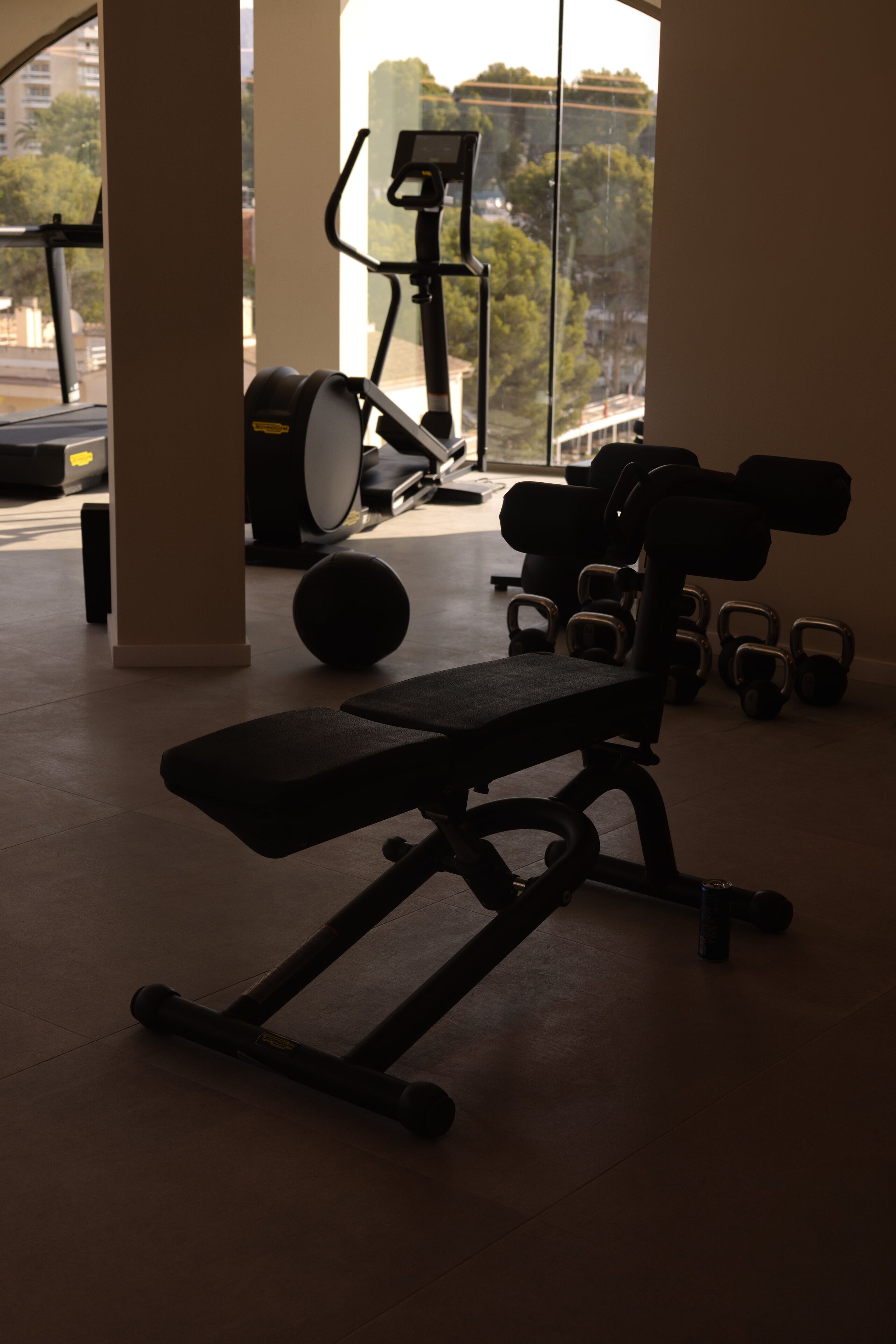 Une salle de sport équipée de matériel d’exercice, notamment un banc, des haltères et un vélo d’appartement.