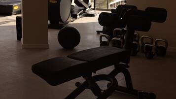 A gym with exercise equipment including a bench, dumbbells, and a stationary bike.