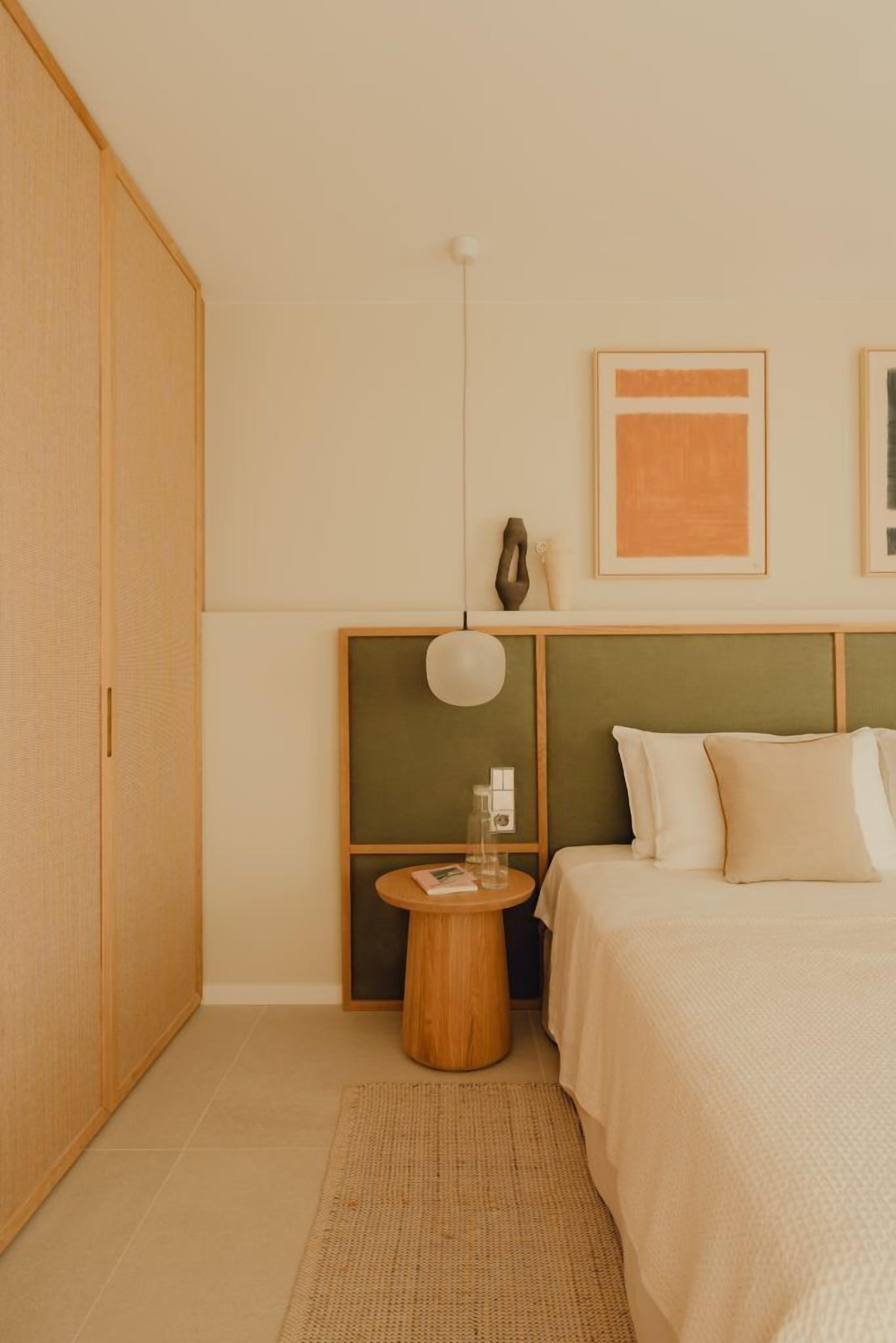 A bedroom with a bed, a bedside table, a lamp, and a wardrobe.