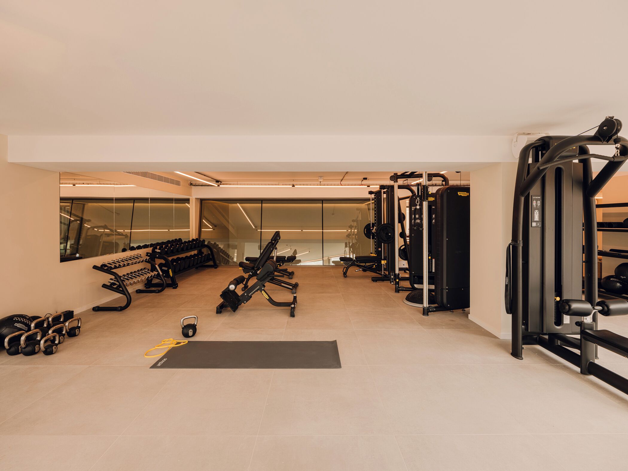 A modern gym with various exercise equipment, including dumbbells, kettlebells, and weight machines.