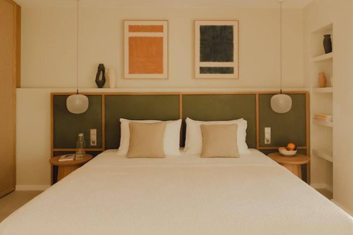A neatly arranged hotel room with a large bed, two bedside tables, and a shelf with decorative items.