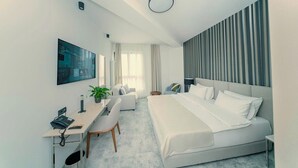 Een moderne hotelkamer met een bed, bureau, stoel en een groot raam.