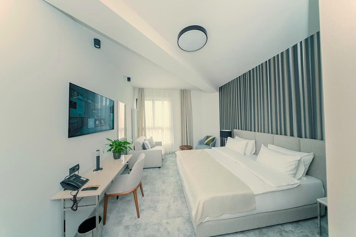 Ein modernes Hotelzimmer mit Bett, Schreibtisch, Stuhl und einem großen Fenster.