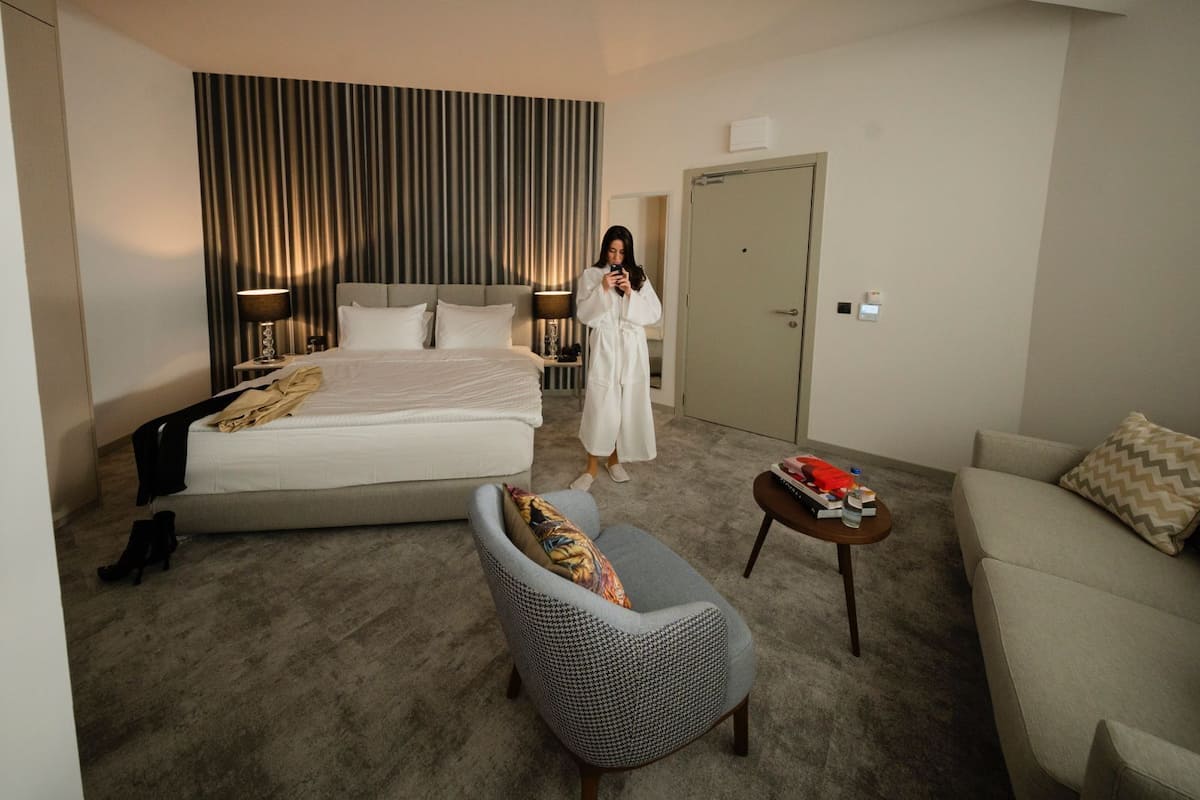 Ein Hotelzimmer mit einem großen Bett, einer Sitzecke mit einem Sessel und einem kleinen Tisch sowie einem Kleiderschrank.