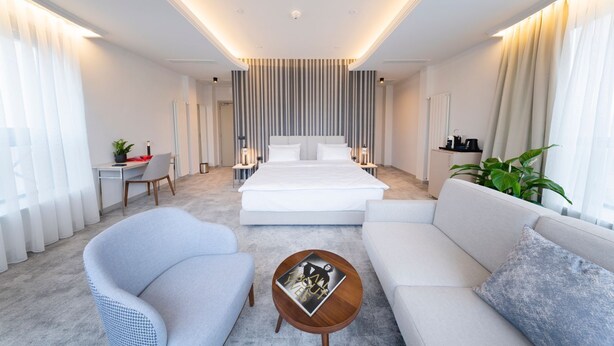 Een moderne hotelkamer met een groot bed, een bank, een stoel, een salontafel en een bureau.