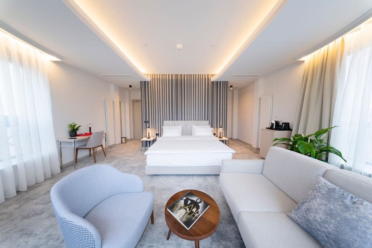 Ein modernes Hotelzimmer mit einem großen Bett, einer Couch, einem Sessel, einem Couchtisch und einem Schreibtisch.