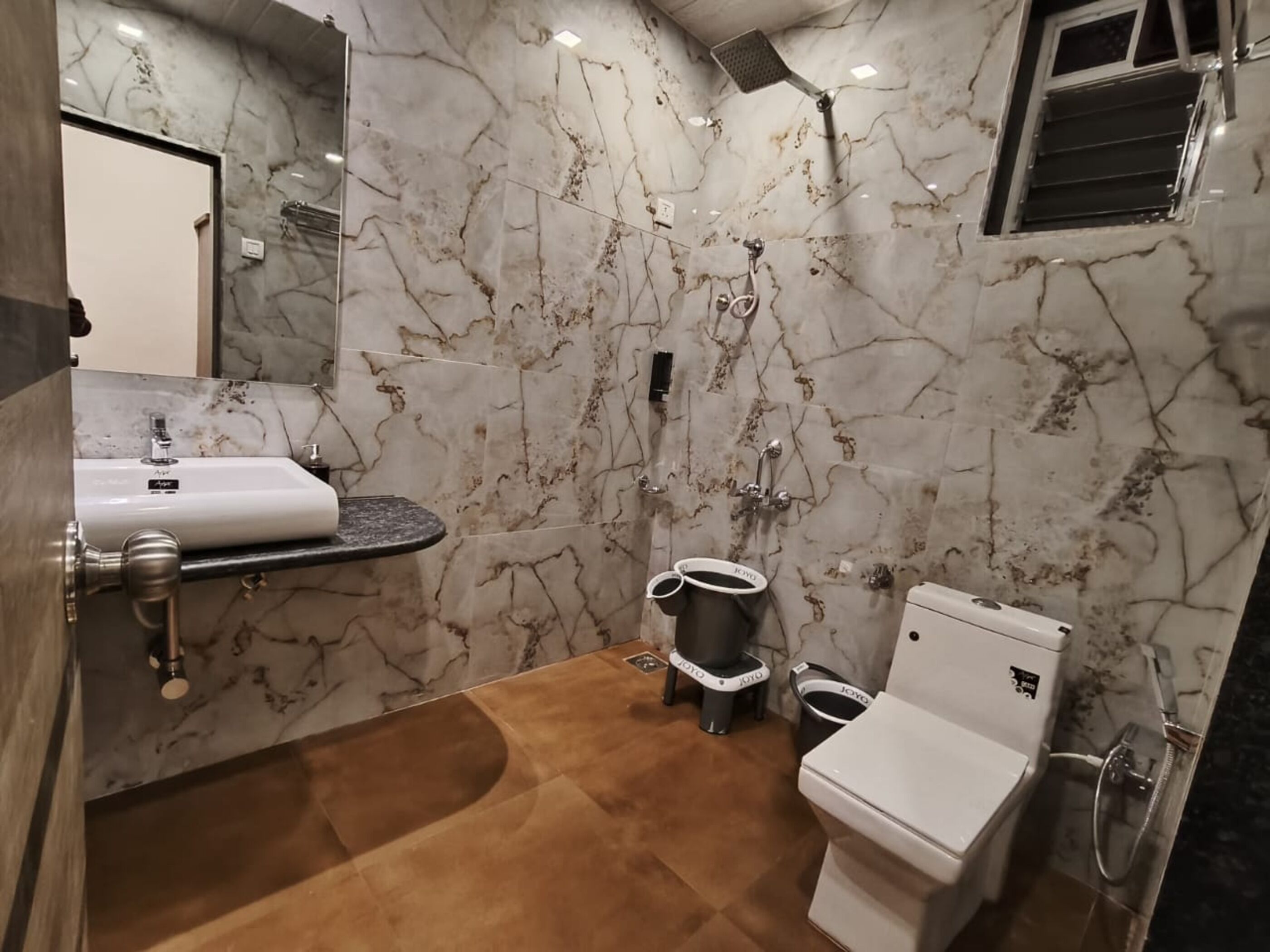 Un bagno con parete in marmo, lavabo, WC e doccia.