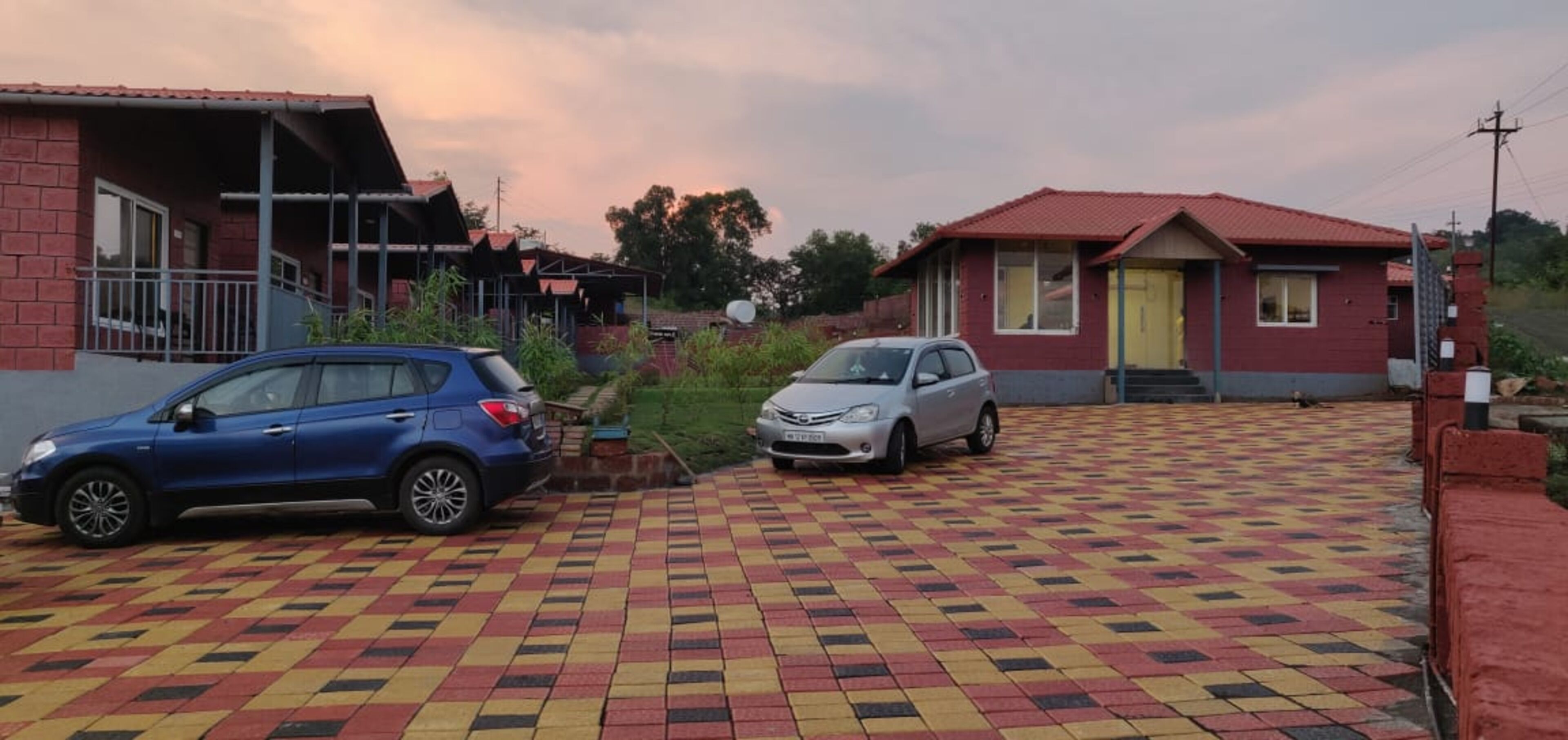 Zona residencial con dos casas y dos coches aparcados en un camino de entrada con diseño.