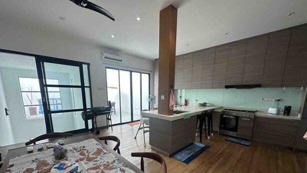 A modern kitchen with a central island, a dining area with a table, and a large window providing natural light. - Nara s Luxe Villa#pooltable#karaoke#partyhouse (Pelabuhan Klang)