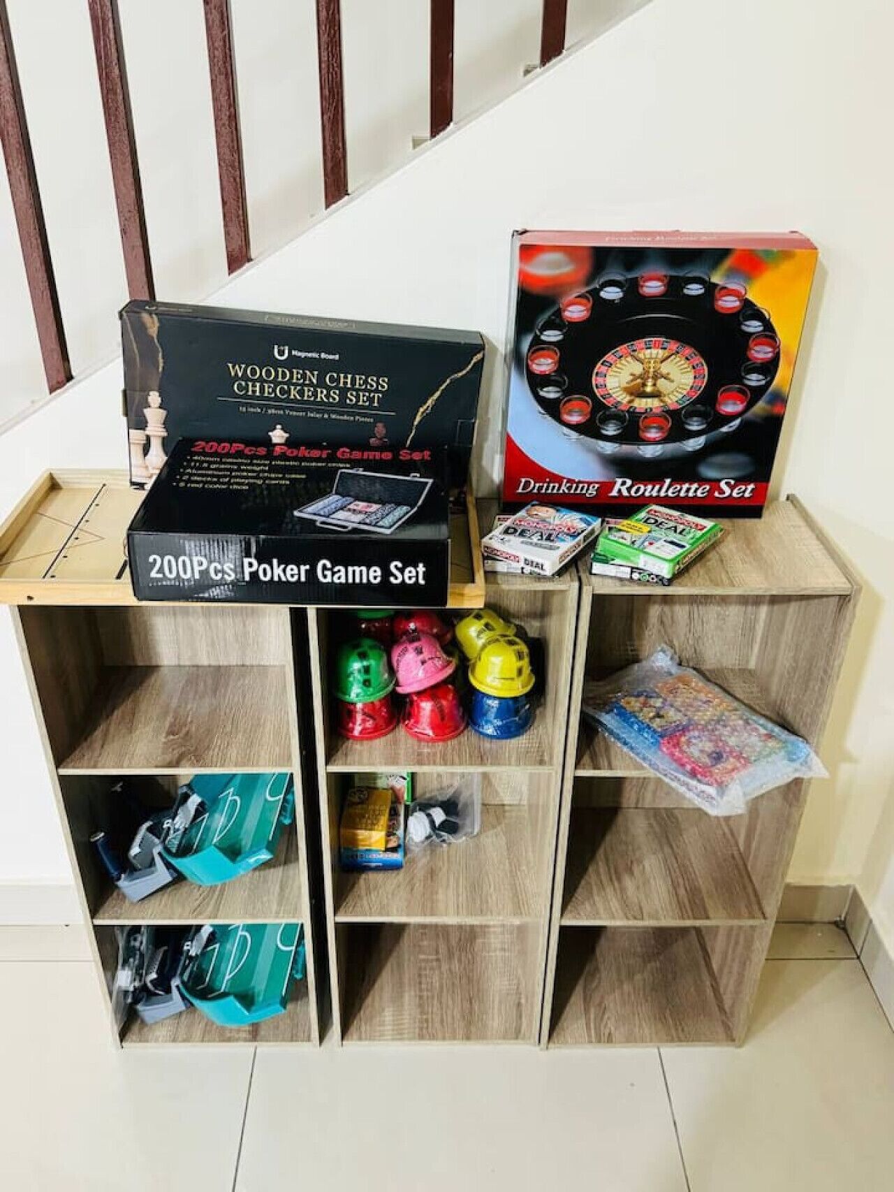 A wooden shelf with various board games and a roulette set.