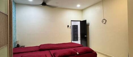 A room with a bed, a ceiling fan, and a door.