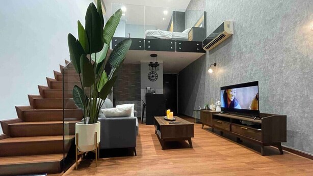 Ein modernes Wohnzimmer mit Treppe, einer Couch, einem Couchtisch und einem Fernseher.