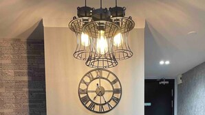 Ein moderner Essbereich mit einem schwarzen Tisch, einer Wanduhr und einer dekorativen Leuchte.