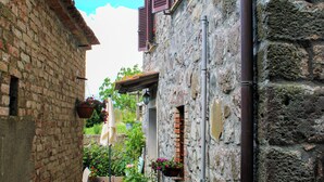 Une ruelle étroite avec un portail noir, des plantes en pot et un vélo.