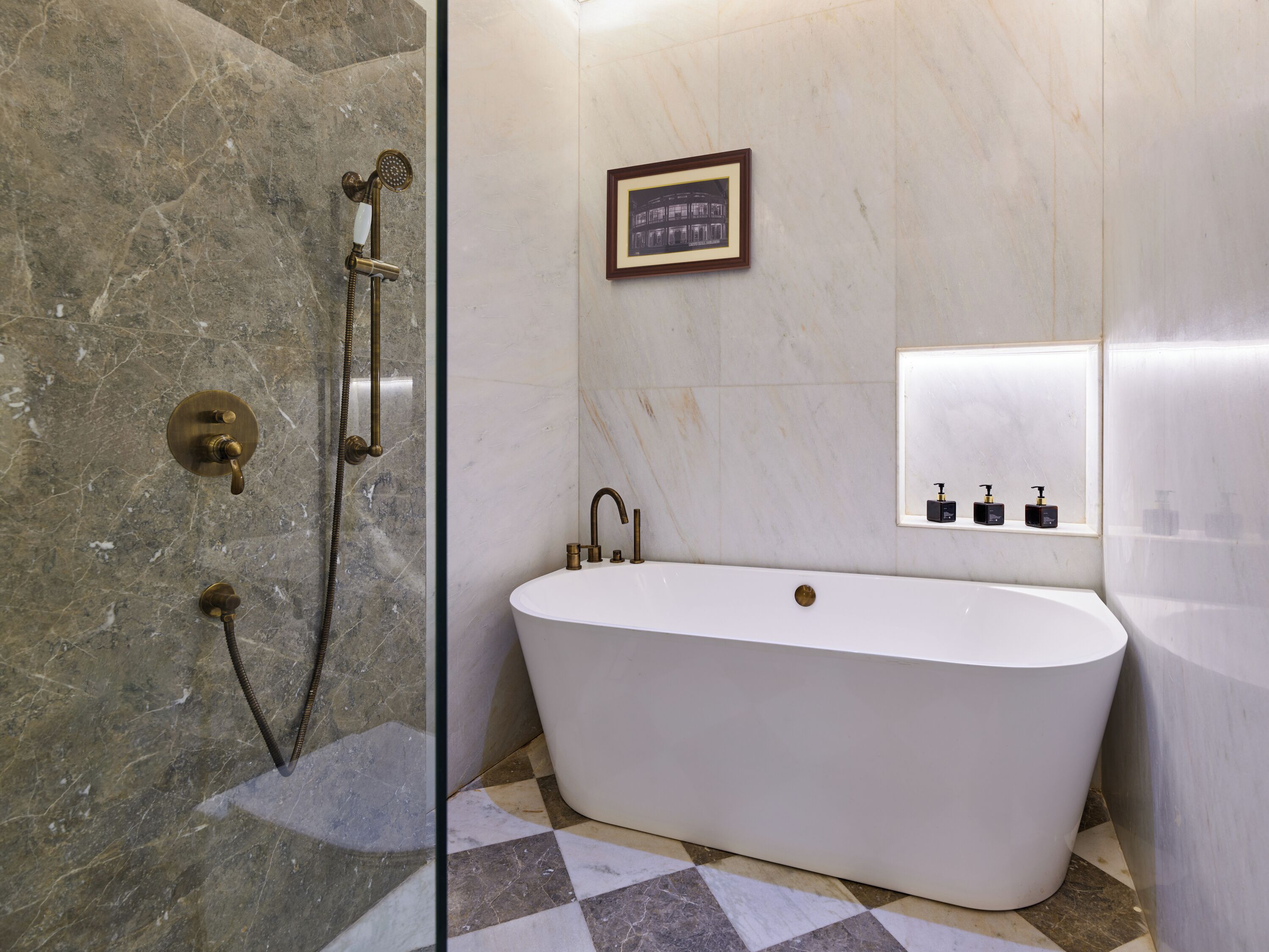 A bathroom with a freestanding bathtub, a shower with a handheld showerhead, and a framed picture on the wall.