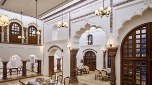 Un gran salón con arcos ornamentales, candelabros y una amplia mesa de comedor dispuesta para un evento formal.
