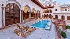 Zona de piscina con tumbonas de madera y piscina cristalina.