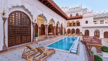 Een buitenzwembad, parasols bij het zwembad en ligstoelen