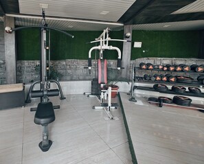 A gym with exercise equipment, a bench, and a rack of dumbbells.