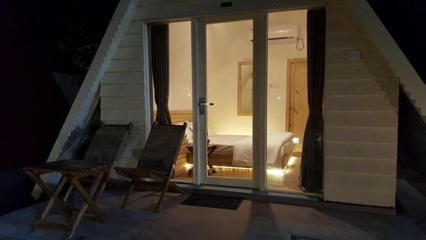 A cozy room with a bed, a chair, and a sliding glass door leading to a balcony. - Panchet Residency (Raghunathpur)
